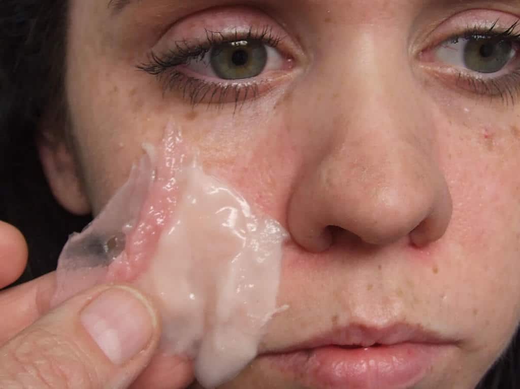 A woman is peeling off her face with a cloth.