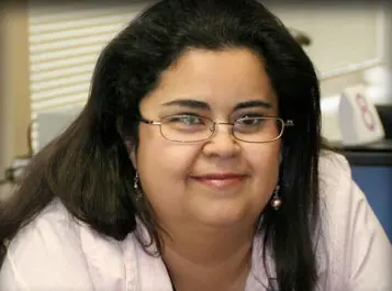 A woman with glasses is smiling for the camera.