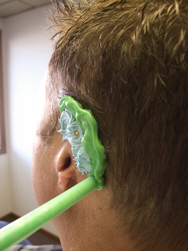 A man with green toothbrush in his ear.