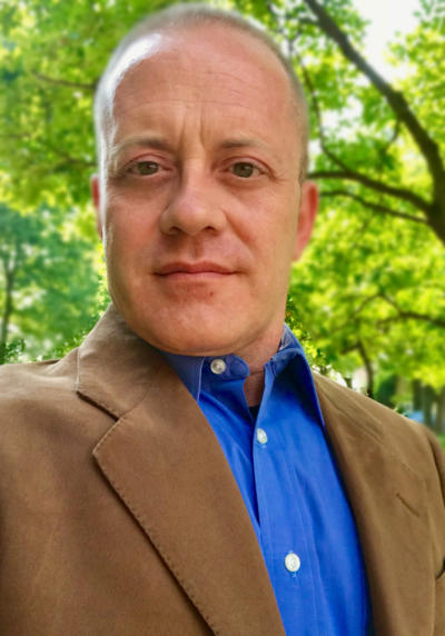 A man in a brown jacket and blue shirt.