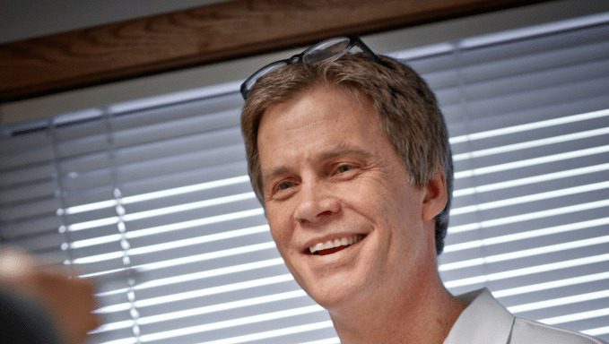 a man smiling with glasses on his head