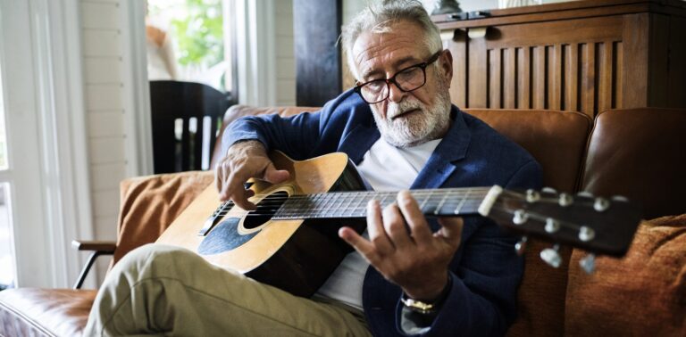 a man sitting on a couch playing a guitar