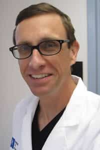 a man wearing glasses and a white coat