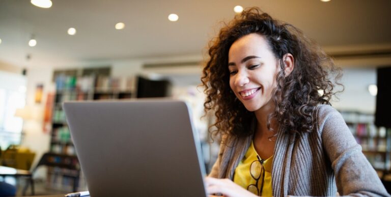 a woman smiling at a laptop